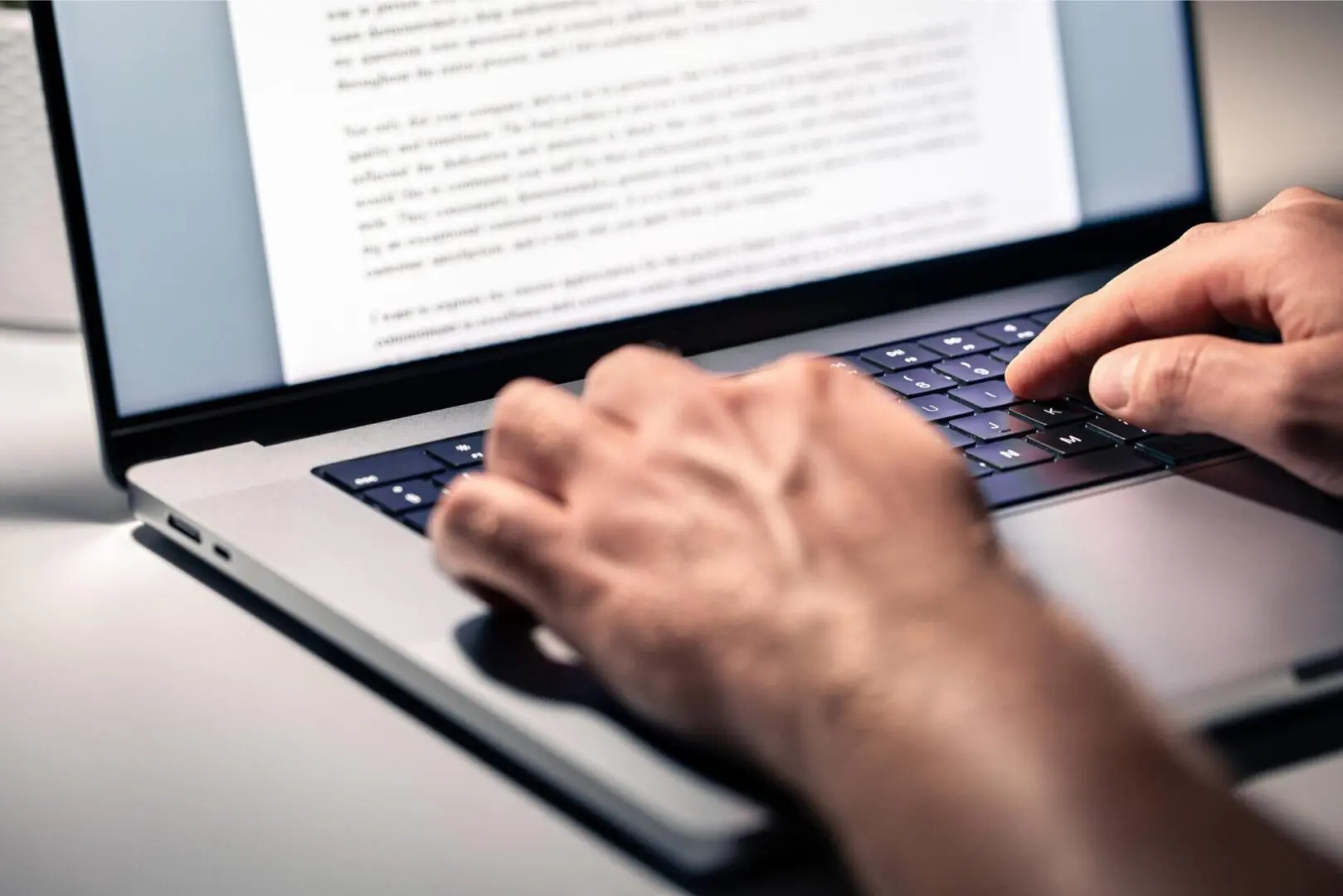 Hands typing on a laptop keyboard.