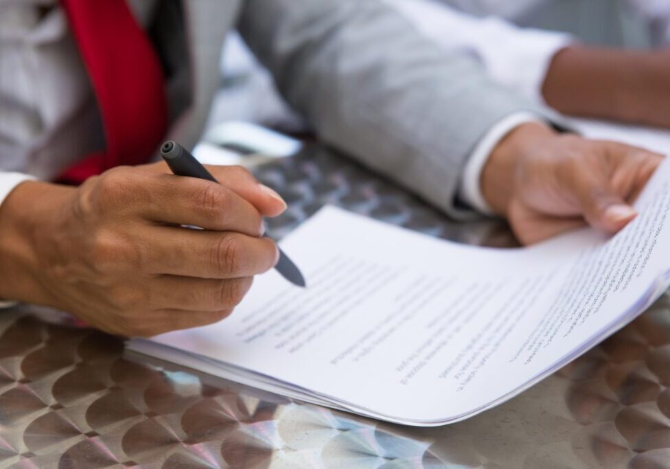 Person signing a document with pen.